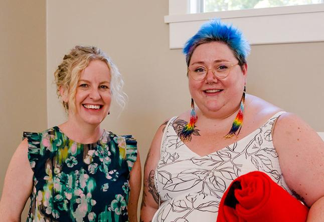 Two women leaders, one with blue hair and rainbow earrings