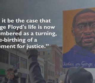 A person in a crowd on the street holds up a painting of George Floyd