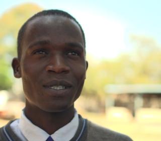 Image: Head shot of a young Black man against a background in Africa