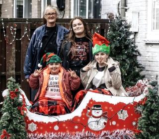 A family of four poses in front of a Christmas tree