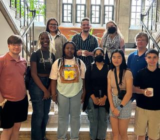 Climate motivators posing as a group on stairs in a historic building in front of bright windows