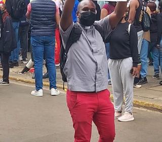 A man wearing a clerical collar holds up a sign that says "The sovereign power belongs with the people." 