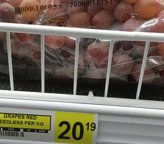 A bag of grapes on a grocery store shelf.