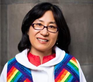 Head shot of HyeRan Kim-Cragg wearing a rainbow-coloured alb around her neck