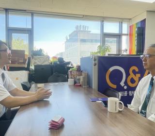 Two men talking together across a boardroom table in an office