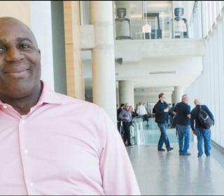 The author, a middle-aged Black man, leans against a wall and smiles.