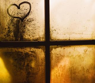 A cross and heart image is seen in a back-lit window with yellow and brown tones.