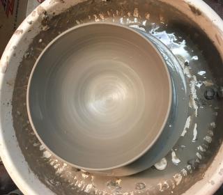 A photo of a potter's wheel, taken from above, showing a spun clay pot.