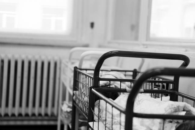 Rows of baby cradles covered with white sheets in this black and white archival photo from a maternity ward.