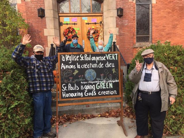 Members of St. Paul's United in Magog, QC, surround sign in front of church