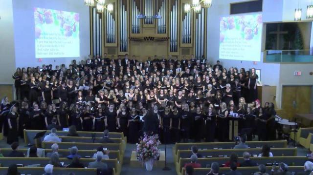 A large choir in robes on the altar, seen from above from a church balcony