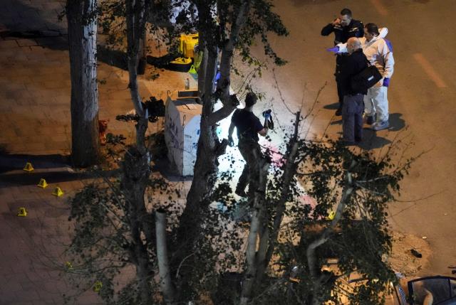 Israeli police inspect the scene of a shooting attack on a street in Israel at night.