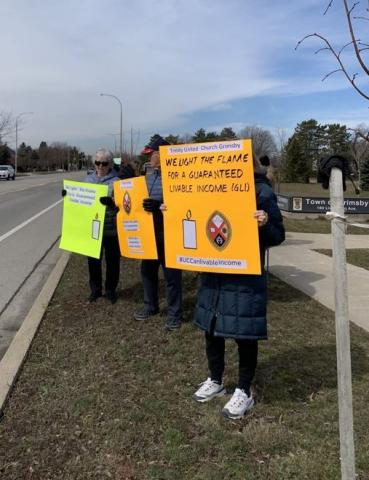 Two people hold up signs supporting a guaranteed livable income.