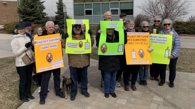 Several people hold signs urging a guaranteed livable income.