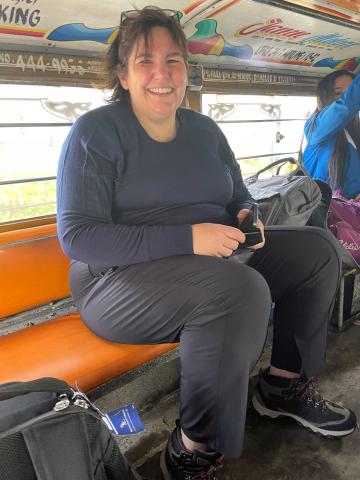 Moderator Carmen Lansdowne sits in the back of a dusty jeepney, a rough covered vehicle used for popular transportation in the Philippines. 