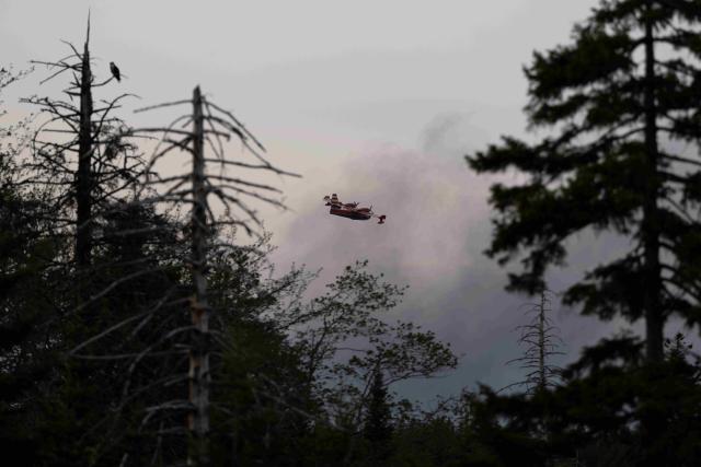 A water bomber plane flies through heavy smoke over a suburban community outside Halifax