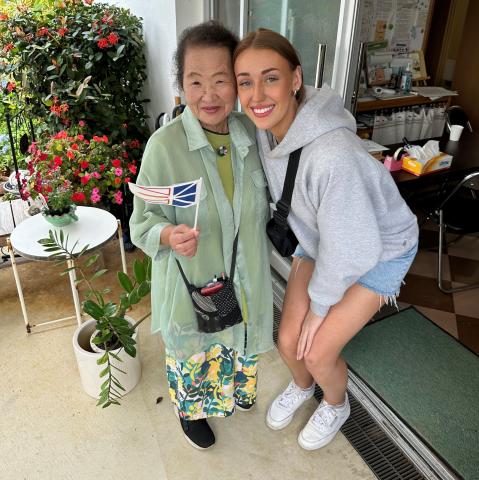 An elderly woman holding a Newfoundland flag poses with a young woman.