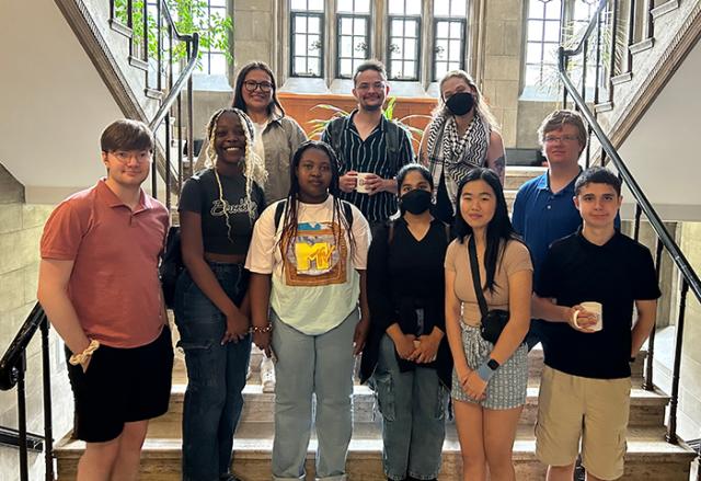 Climate motivators posing as a group on stairs in a historic building in front of bright windows