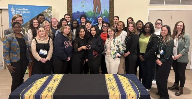 Large group of young people pose in front of Canadian Foodgrains Bank banner