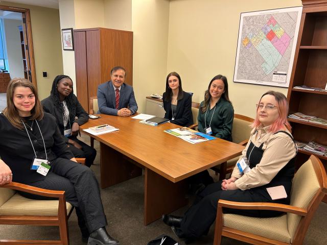 Six young people and a man sit around a conference table 