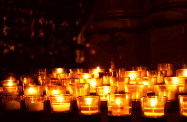 Many lighted votive candles in the dark