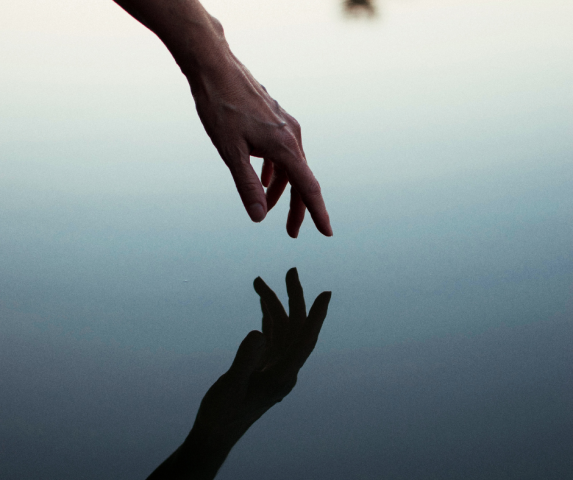 A hand reflected in calm water