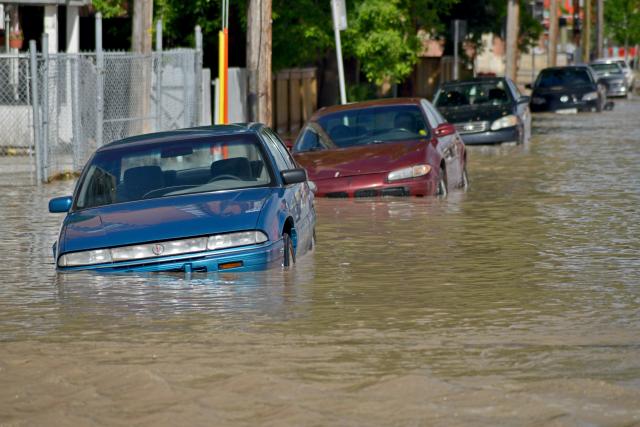 Parked cars on a Calgary street are almost covered in flood waters