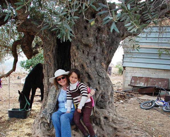 Rev. Juanita Austin and a little Palestinian girl cuddled up in a 1,000 year old olive tree. 