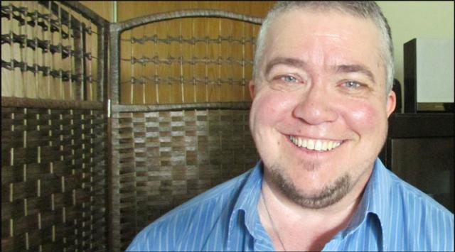 Jordan Sullivan, a White man with blue eyes and a goatee, smiles brightly at the camera.