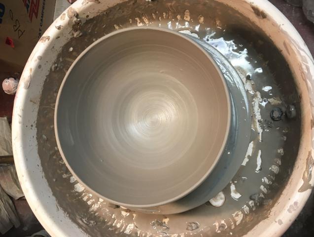 A photo of a potter's wheel, taken from above, showing a spun clay pot.