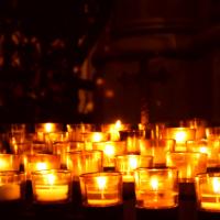 Many lighted votive candles in the dark