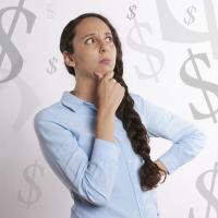 A woman surrounding by money symbols, pondering finances.