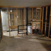 The interior of a house, stripped to the frames, with plumbing and electrical wires revealed.